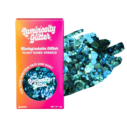 Luminosity Glitter packaging with biodegradable and plant-based sparkle, next to a handful of blue glitter.