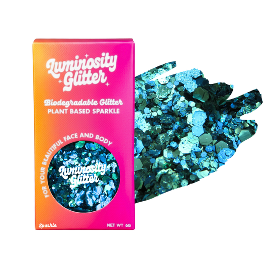Luminosity Glitter packaging with biodegradable and plant-based sparkle, next to a handful of blue glitter.