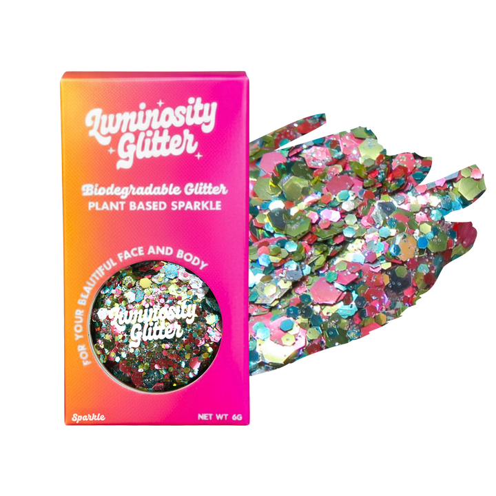 Luminosity Glitter packaging with biodegradable and plant-based sparkle, next to a handful of colorful glitter.
