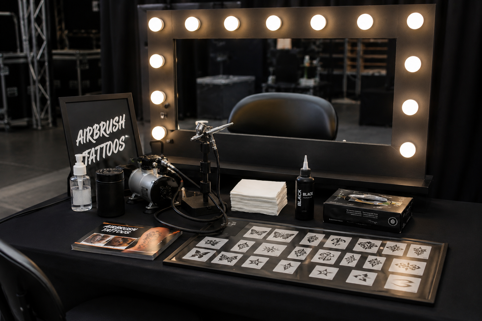 A black airbrush tattoo station with a sign, hollywood mirror, black ink and designs to choose from