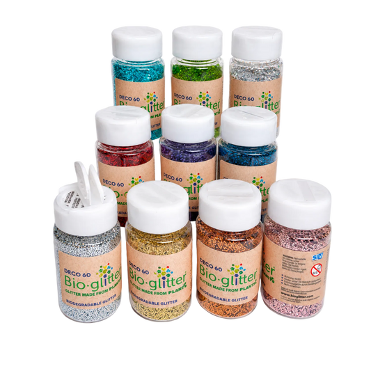 Eight small jars of craft Bioglitter in various colours, arranged on a plain white background. The jars have white screw caps, tan labels, and are filled with different coloured glitter.