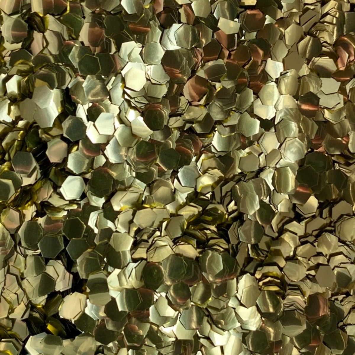 A close-up image of gold super chunky eco glitter, showing the reflective and three-dimensional texture of the sequins.