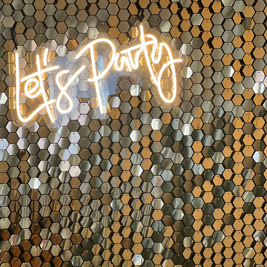 gold luxury sequin wall hire with a lets party neon sign in warm white